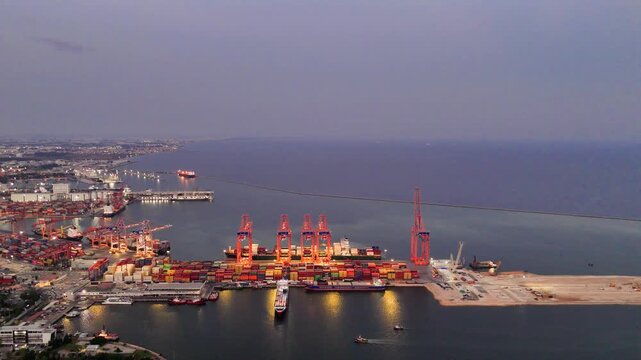 Drone films seaport at sunset, capturing port activities Port operations highlight significance of business logistics Business activities at port demonstrate importance of maritime trade and commerce