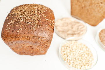 Rye bread with cumin on a white background and bowls with ingredients. Selected focus.