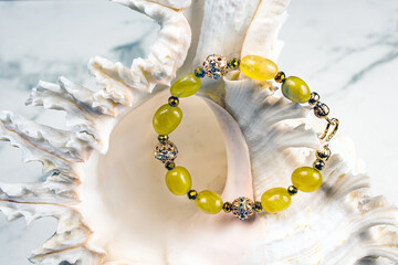 Delicate yellow opal bracelet against the background of the sea shell.