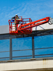 Elevated pedestrian overground tunnel facade painting using a telescopic boom lift with a basket