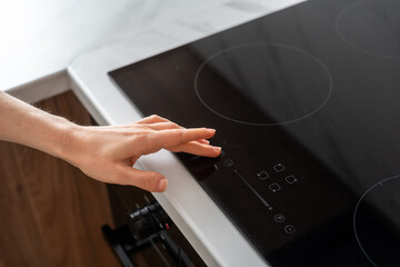 Hand adjusting electric stove top burner in kitchen