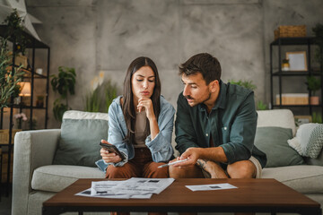 Adult serious couple sit and calculate their monthly domestic finances