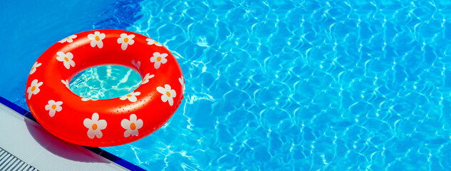 Bright red inflatable ring with a pattern of daisies on the edge of the pool