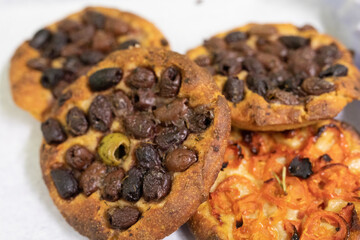 A pile of focaccia bread topped with olives and tomatoes