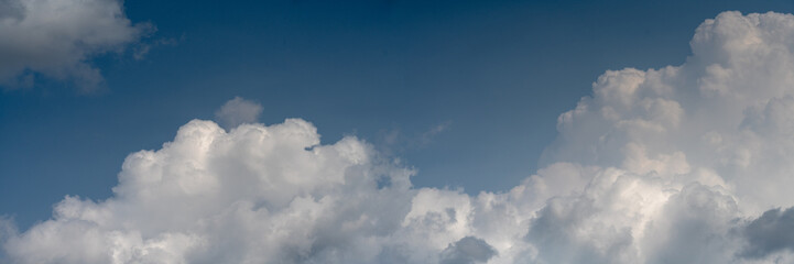 Panorama of beautiful white summer clouds in a blue sky.  Cumulus puffy clouds.
