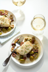Bright Summer Herb and Olive Fish Fillet  on two plates with white wine