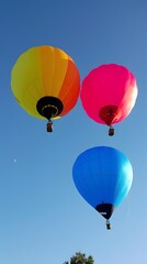 Fototapeta premium Three Colorful Hot Air Balloons Flying in Blue Sky