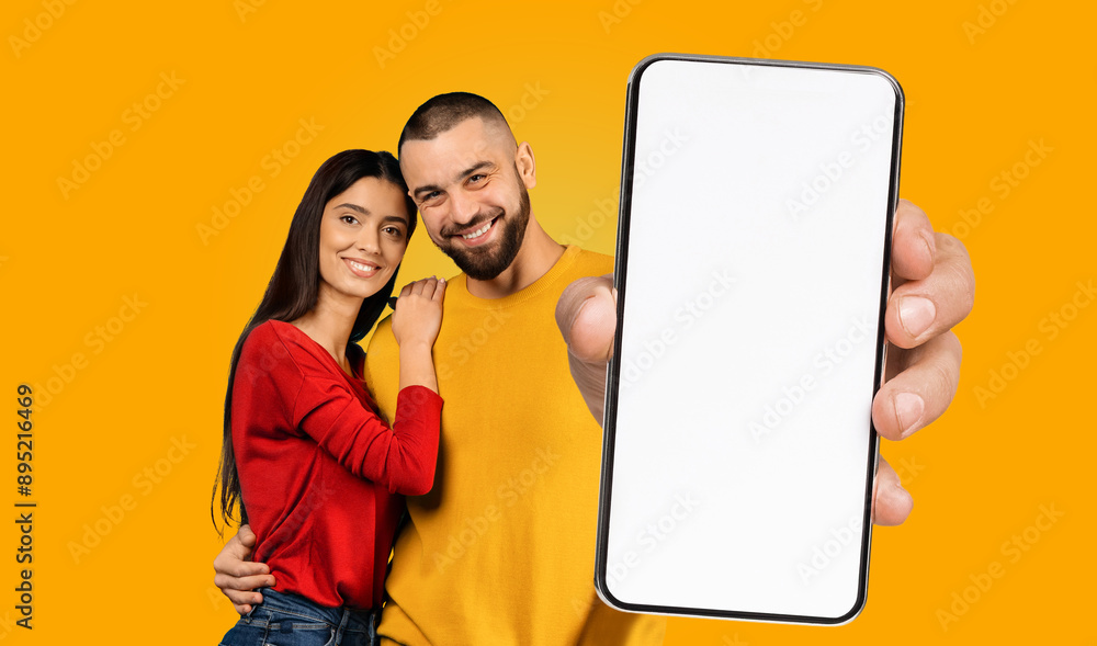 Aufkleber a happy young couple stands together in front of a yellow background, smiling at the camera. the man