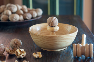 A walnut on top of a walnut breaking tool with some walnuts in the foregorund and some in the background in a beautiful kitchen