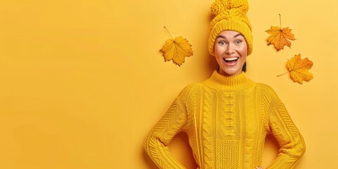 A woman in a yellow sweater and hat beams with happiness surrounded by falling leaves against a vibrant yellow background