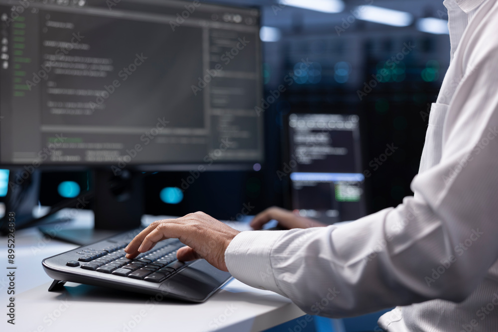 Poster it administrator working on pc in hardware room housing server rackmounts, storage devices and netwo