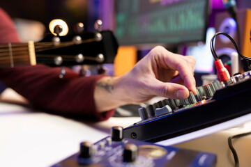 Audio engineer working with stereo equipment and control panel board, mixing and mastering tunes in...