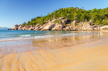 Picturesque golden sandy Alma Beach with granite boulders and turquoise water on Magnetic Island, Queensland, Australia.