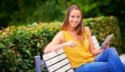 Obraz premium Tablet, woman and outdoor portrait for study, research and networking for university project. College student, happy and technology on bench in park for social media, connection and online for ebook