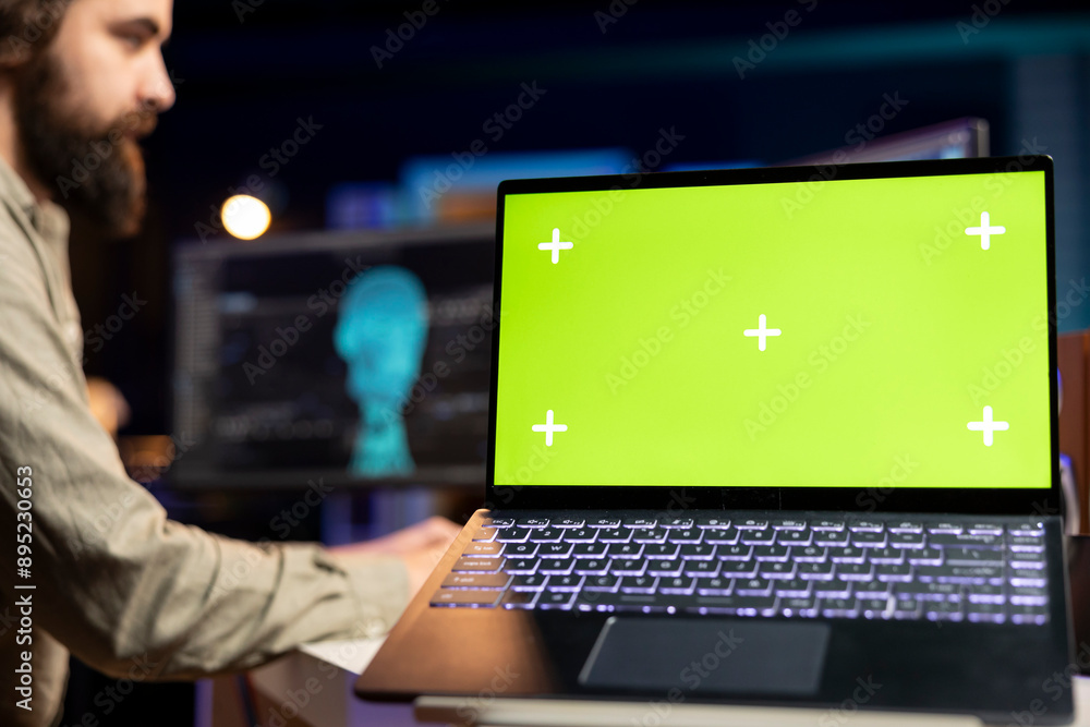 Poster focus on green screen laptop used by engineer wearing eeg headset in blurry background to upload con