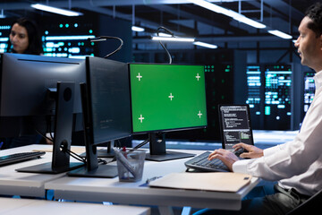 IT operators in data center checking equipment performance on isolated screen computer after upgrading infrastructure. Admins doing maintenance on supercomputers in servers room using chroma key PC