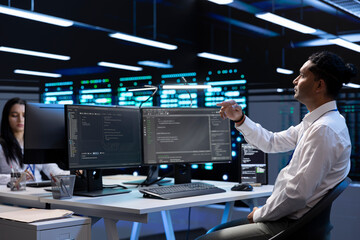 System administrator looking at holograms in data center, monitoring equipment. IT staff member in...