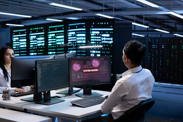 Teamworking developers in server room trying to protect hardware from cybercriminal attack. Data...