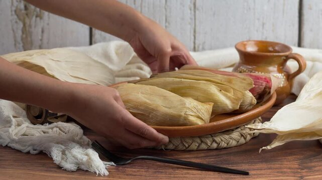  Latin woman places a traditional clay plate on the table with tamales of different flavors