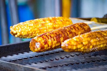 the corns being grilled over charcoal