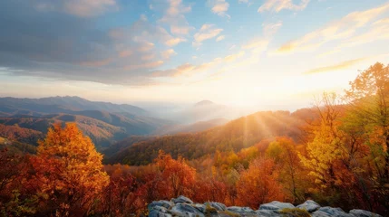 Fleecedeken met foto A beautiful mountain view with a bright orange sun shining on the trees. The sky is clear and the mountains are covered in autumn foliage © Sasikharn