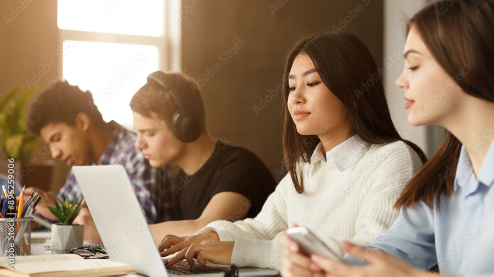 Poster a vibrant group of multiracial students studies together in a library, each using various devices. t