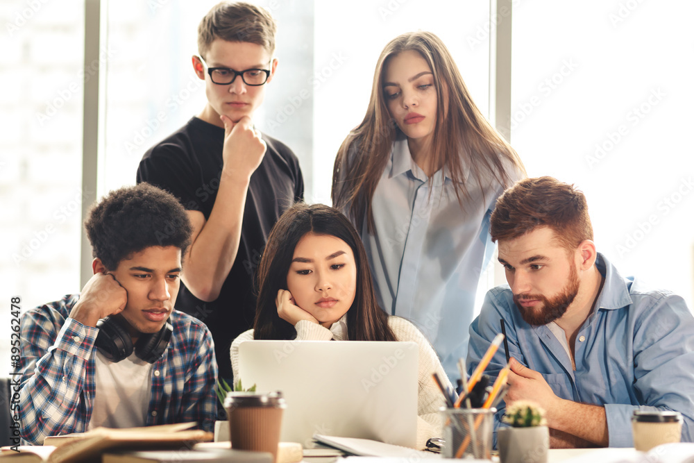 Poster a group of five young professionals is gathered around a laptop, collaborating intently on a project