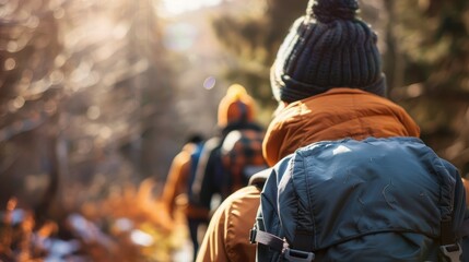 A group of individuals wearing backpacks are hiking through a forested area during winter, displaying an outdoor adventure in a natural setting.