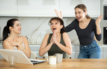 Fototapeta premium Women are sitting at computer and are immensely happy, exclaim joyfully and are fortunate to receive good news about win