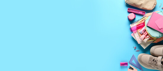 School supplies with backpack on blue background. Top view