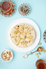 Tasty Tahini halva with pistachios and glasses of Turkish tea on blue background
