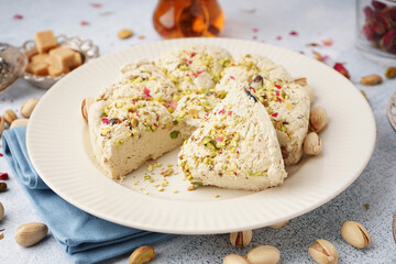 Plate of tasty Tahini halva with pistachios on light background