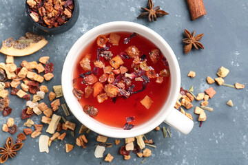 Cup of tea and scattered dried fruits on grey grunge background