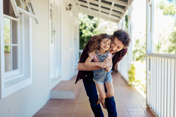 Father playing with daughter on porch