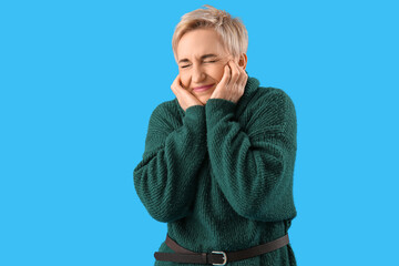 Scared mature woman on light blue background