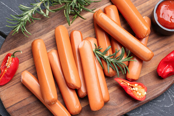 Board with tasty sausages on dark wooden background