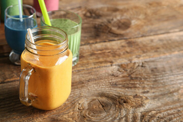 Mason jar of yellow smoothie on wooden background