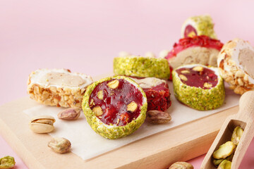 Wooden board with tasty Turkish delight on pink background