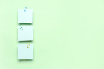Sticky notes with paper clips on green background