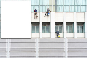 Blank poster on a building facade. Window washers at work.