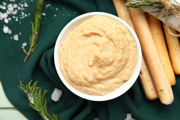 Bowl with tasty hummus and Italian Grissini on table, closeup