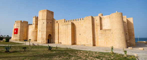 Scenic view of robust stone outer walls with strategic watchtowers of medieval Ribat of Monastir,...