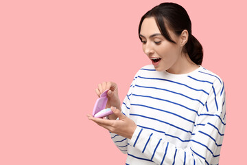 Beautiful young woman with tampons storage box on pink background