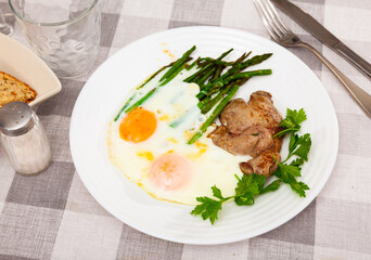 Vibrant breakfast of delicate roasted rabbit liver paired with perfectly fried eggs and asparagus, garnished with fresh parsley