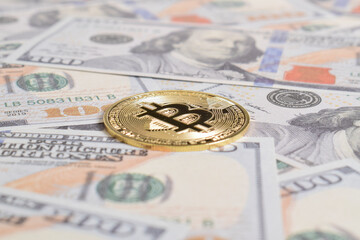 Golden symbolic coin Bitcoin on banknotes of one hundred dollars. Exchange bitcoin cash for a dollars. Cryptocurrency on US dollar bills. Savings, investments concept. Digital modern method of payment