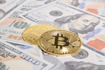 Golden symbolic coin Bitcoin on banknotes of one hundred dollars. Exchange bitcoin cash for a dollars. Cryptocurrency on US dollar bills. Savings, investments concept. Digital modern method of payment