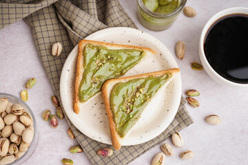 Bread pieces with tasty pistachio paste and cup of coffee on light background