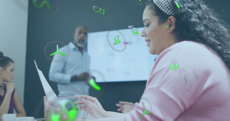 Image of ecology icons over diverse colleagues having meeting in office