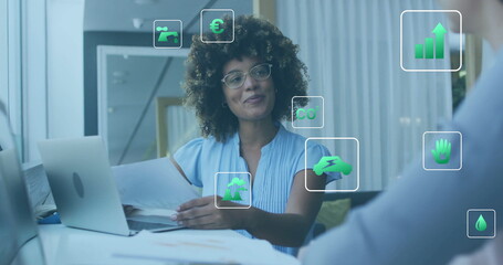 Image of ecology icons over diverse colleagues using laptop and discussing work in office