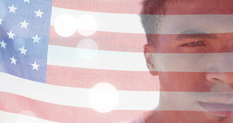 Naklejka premium Image of american flag and light spots over half portrait of happy biracial man on sunny beach